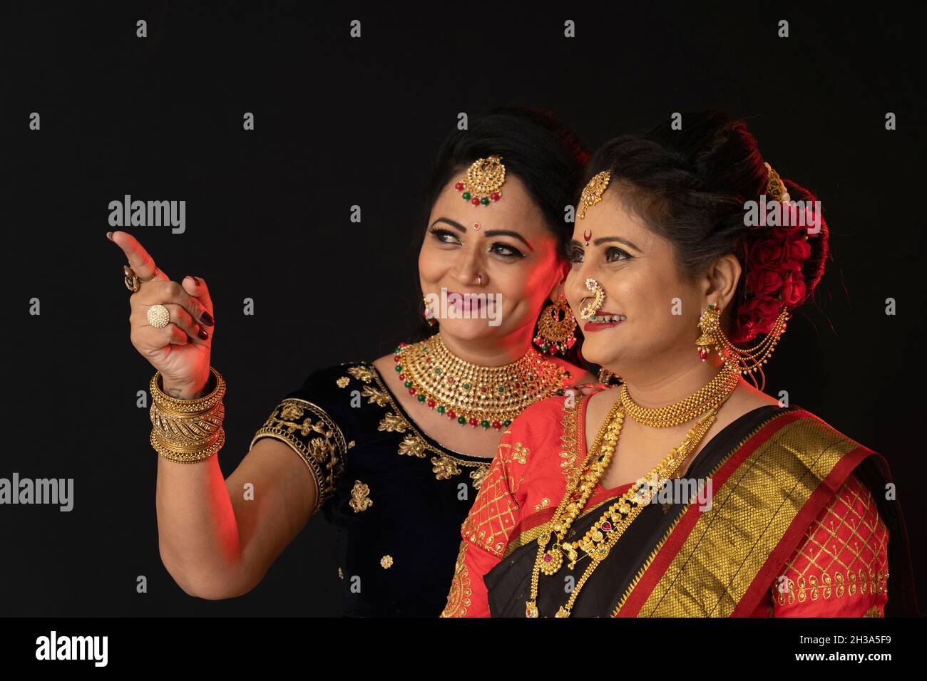 Indische Marathi Frauen in traditionellem Saree und schwerem Goldschmuck. Blick auf die Kamera. Lächelnd. Zwei Frauen Stockfoto