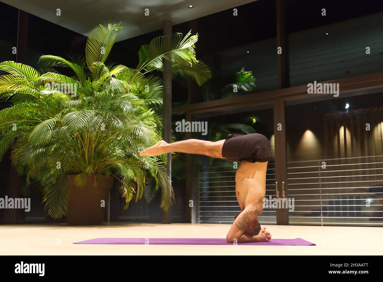 Gutaussehender kaukasischer Mann mittleren Alters führt eine Yoga-Position im Haus durch. Stockfoto