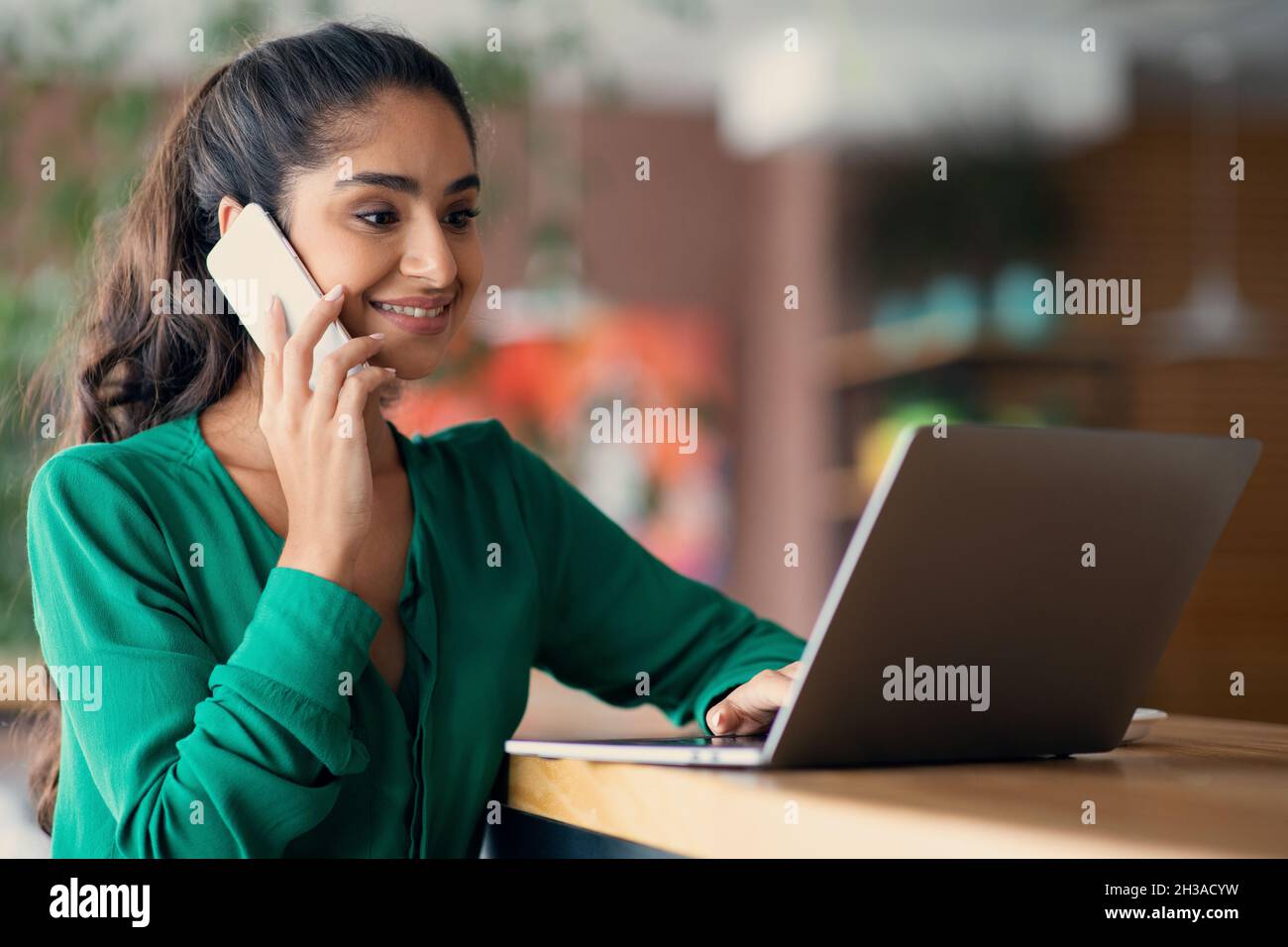 Erfolgreiche arabische Frau, die online arbeitet, Telefongespräche führt, Speicherplatz kopiert Stockfoto