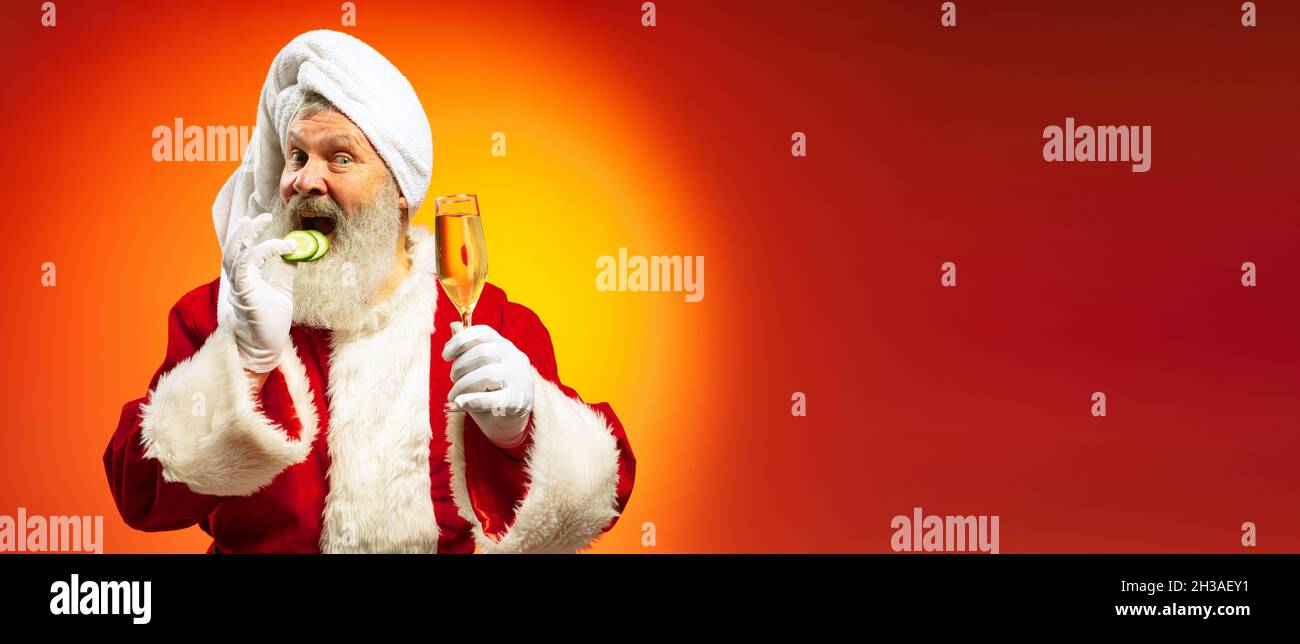 Lustiger älterer Mann mit weißem Frottee und Kostüm des Weihnachtsmannes gratuliert allen mit Neujahr 2022 isoliert auf rot gelbem Hintergrund in Neon. Stockfoto