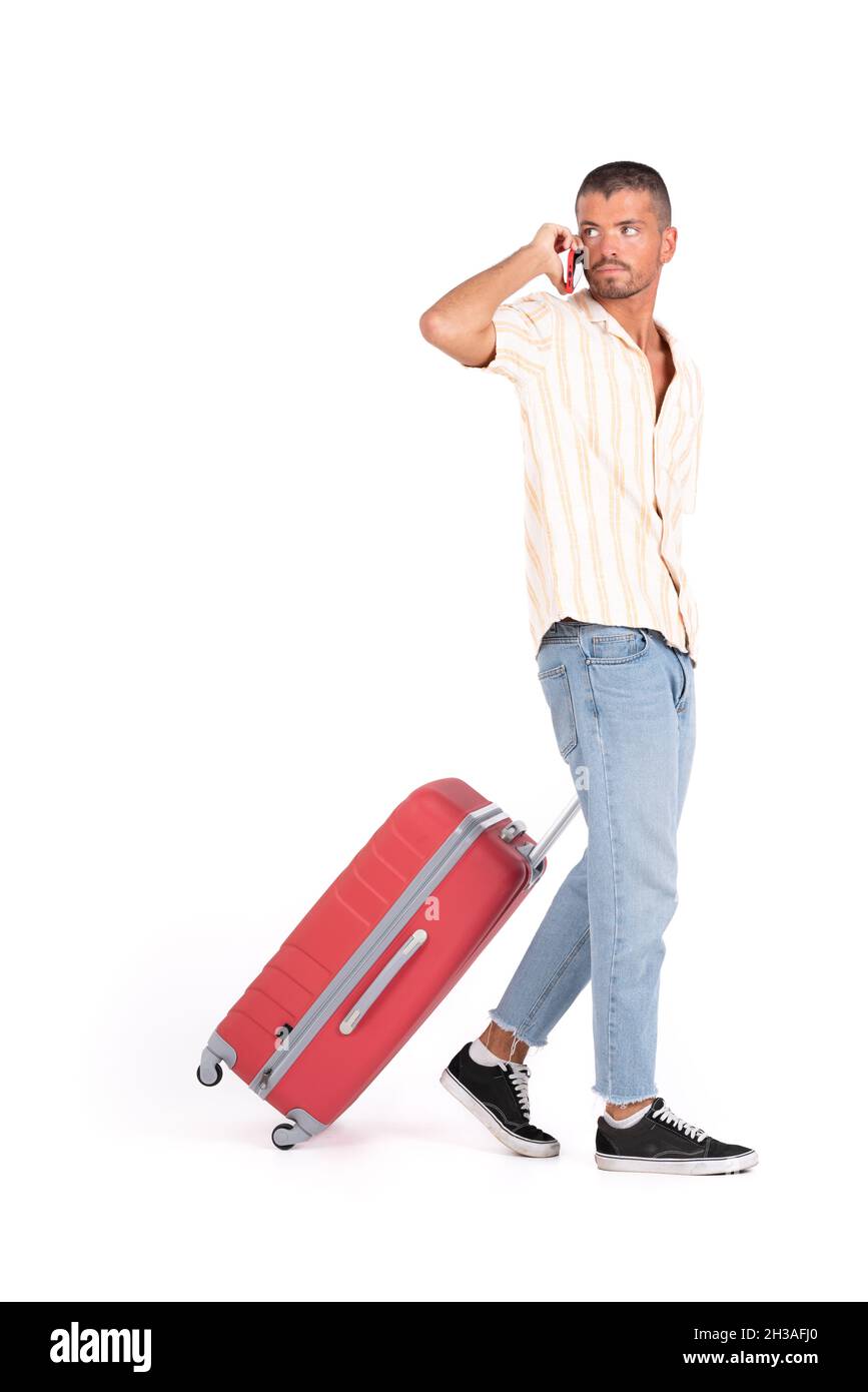 Isolierter Mann mit Reisekoffer, der am Handy herumläuft und spricht Stockfoto