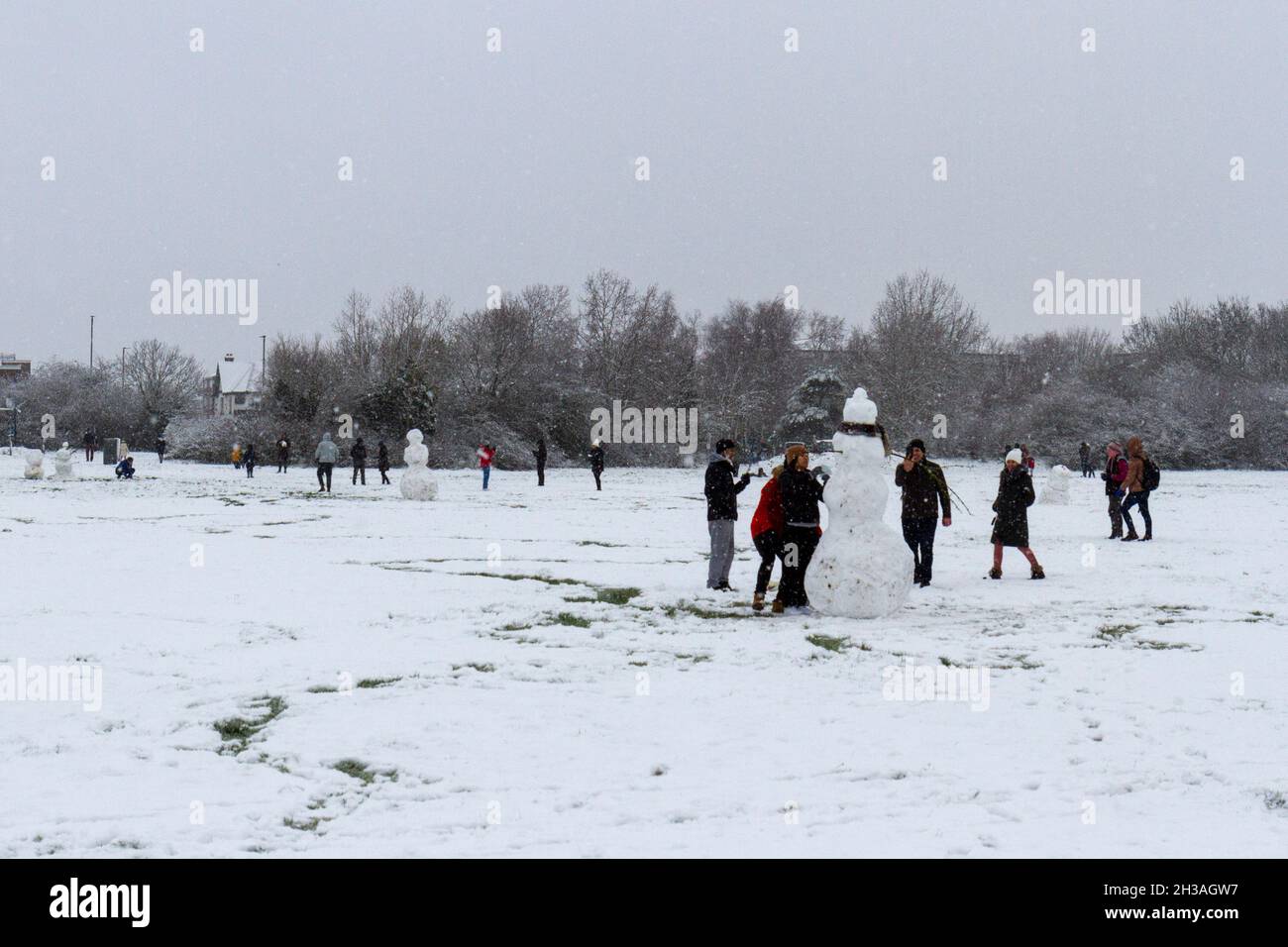 Allgemeine Ansicht von Menschen, die während eines schweren Schneesturms am 24. Januar 2021 Schneemänner auf der Hounslow Heath bauen. Stockfoto