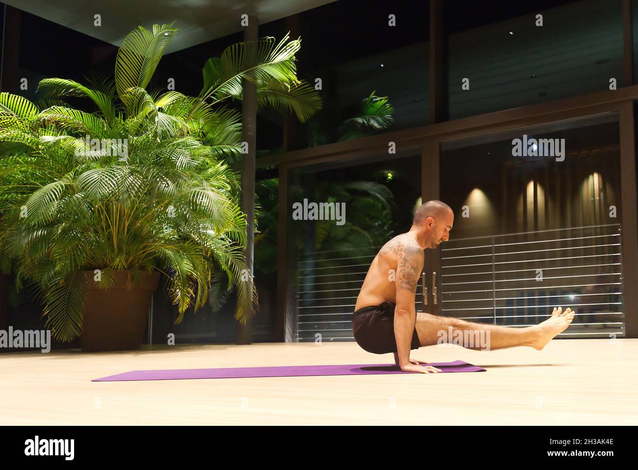 Gutaussehender kaukasischer Mann mittleren Alters führt eine Yoga-Position im Haus durch. Stockfoto