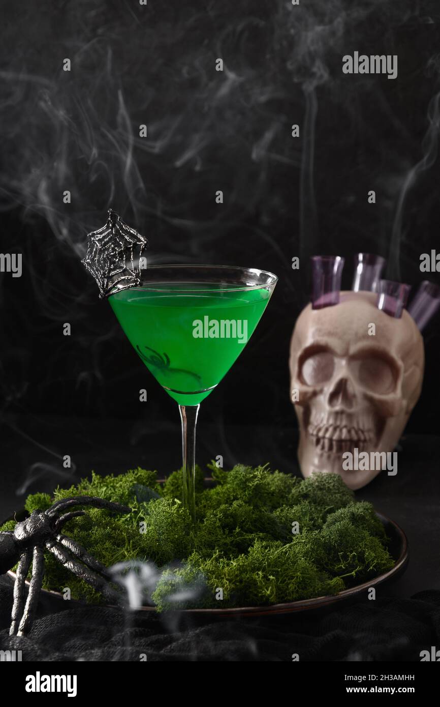 Halloween grüne Cocktails mit Totenköpfen, Spinnen und Rauch auf schwarzem Hintergrund. Horror lustiges Essen. Stockfoto