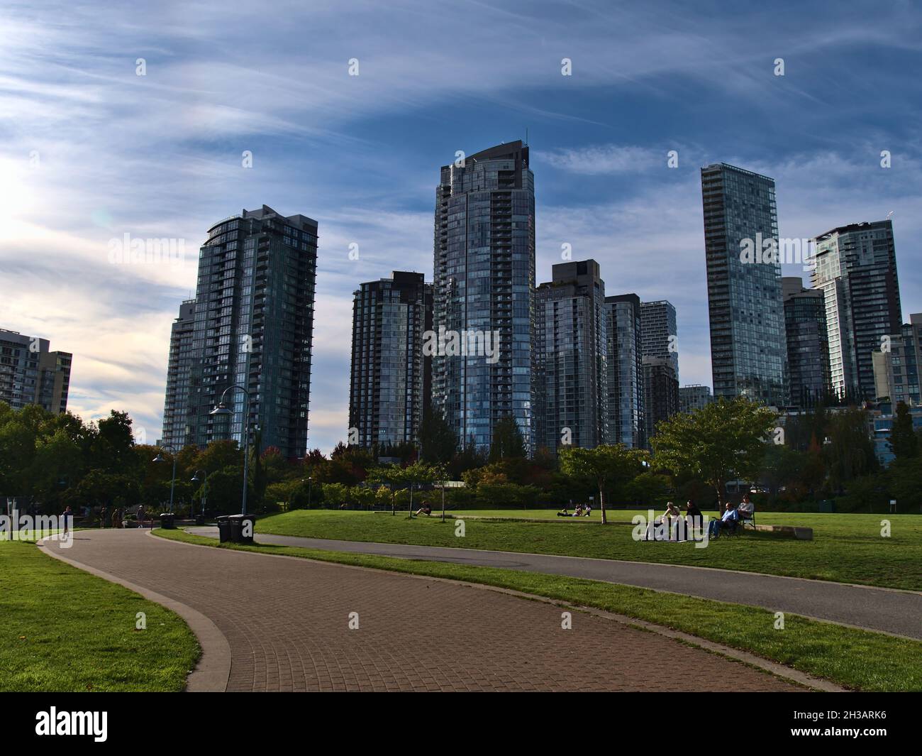Wunderschöne Aussicht auf den David Lam Park in der Innenstadt von Vancouver am False Creek, wo die Menschen die Nachmittagssonne genießen und Hochhäuser mit Wohngebäuden. Stockfoto
