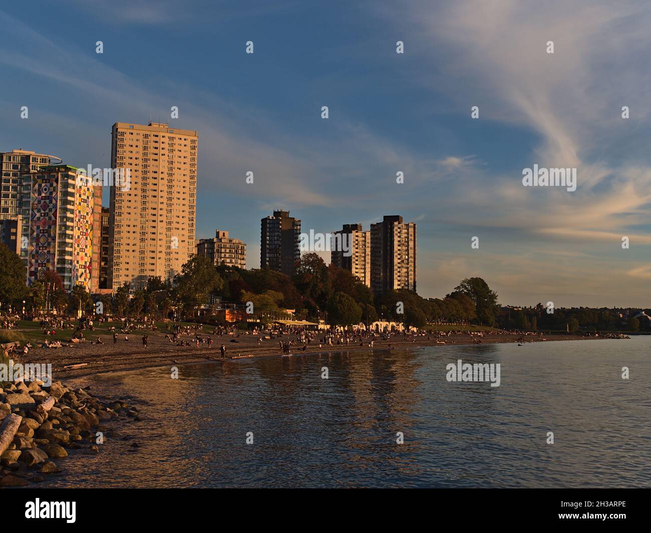 Wunderschöner Blick auf den English Bay Beach im Vancouver-Viertel West End am Ufer des pazifischen Ozeans mit Menschen, die den Sonnenuntergang und die Gebäude genießen. Stockfoto