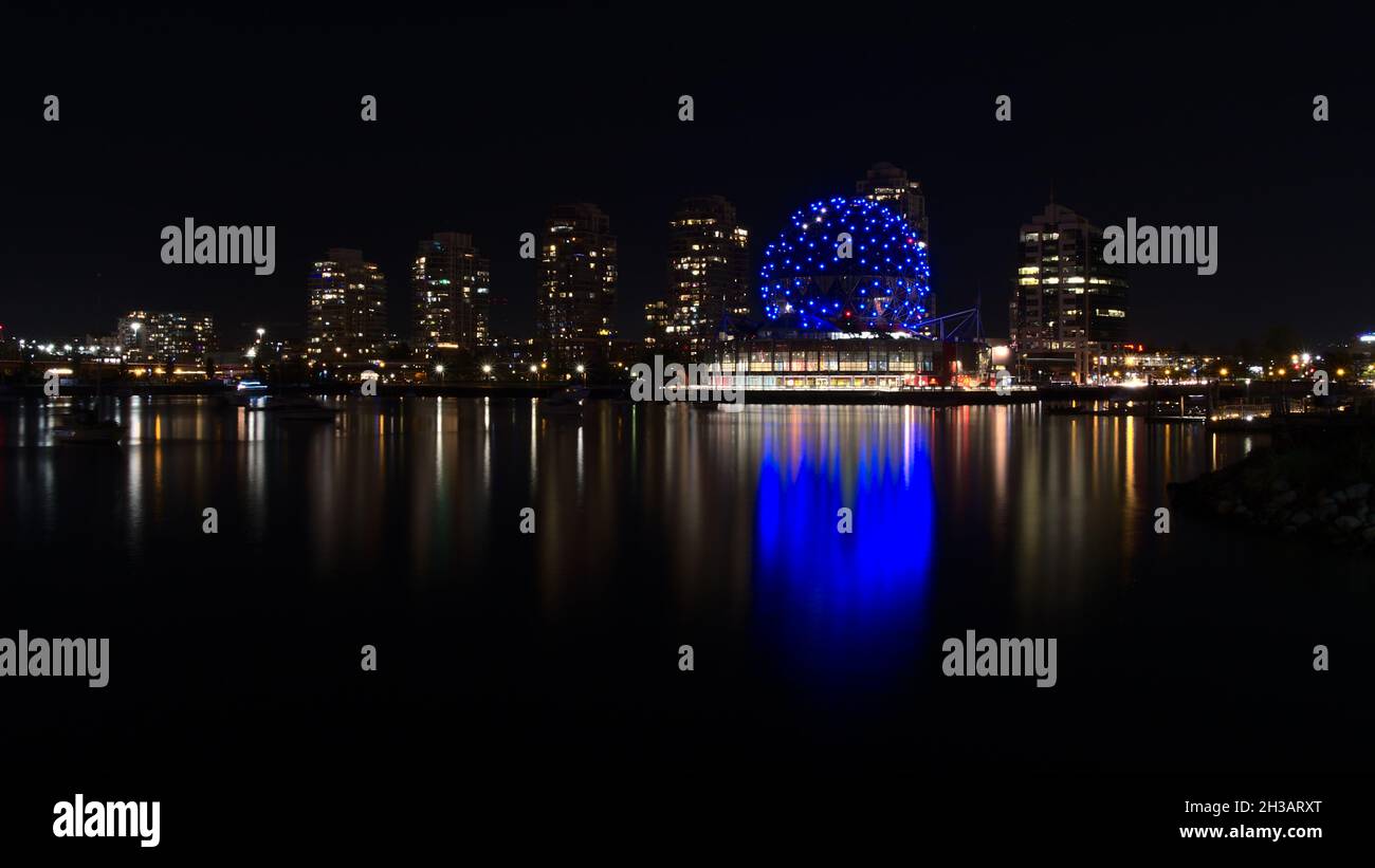 Atemberaubender Blick auf die Bucht von False Creek, Vancouver mit blau glänzender Science World und beleuchteten Gebäuden, die sich nachts im glatten Wasser spiegeln. Stockfoto