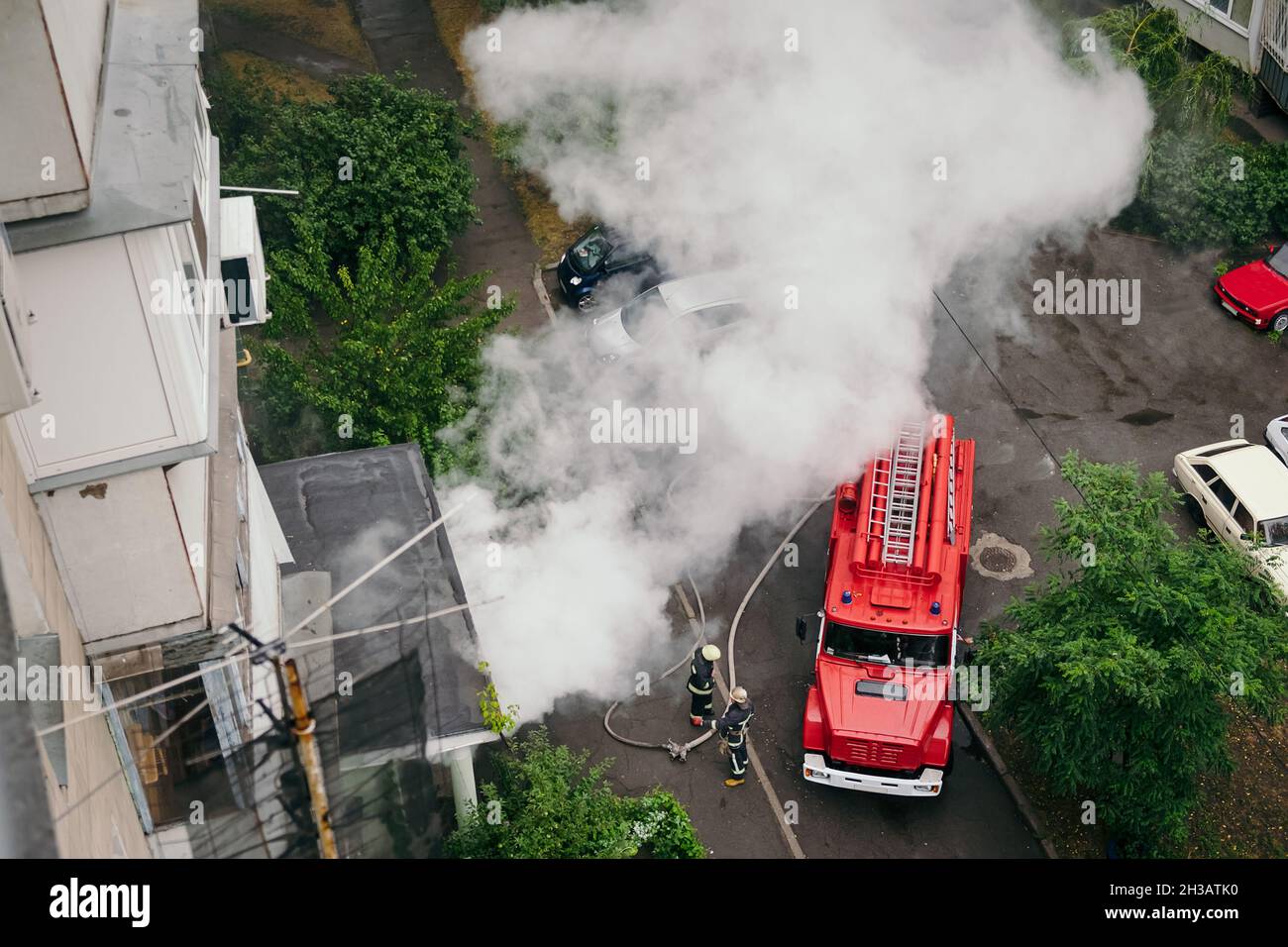 Feuerwehrleute kamen in Feuerwehrautos in das Wohnhaus in der Großstadt und löschen das Feuer. Stockfoto