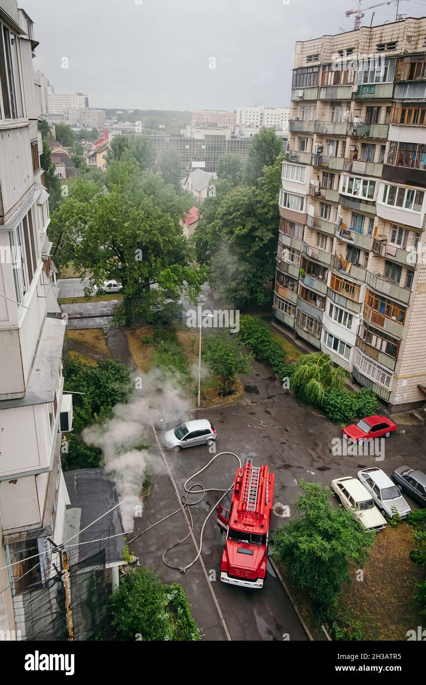 Feuerwehrleute kamen in Feuerwehrautos in das Wohnhaus in der Großstadt und löschen das Feuer. Stockfoto
