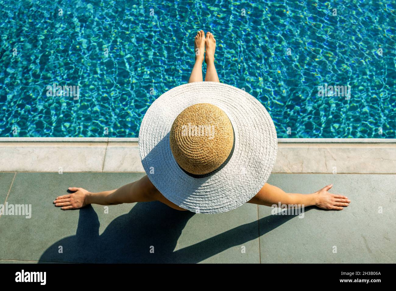 Frau mit Strohhut Sonnenbaden und entspannen am Pool. Draufsicht Stockfoto