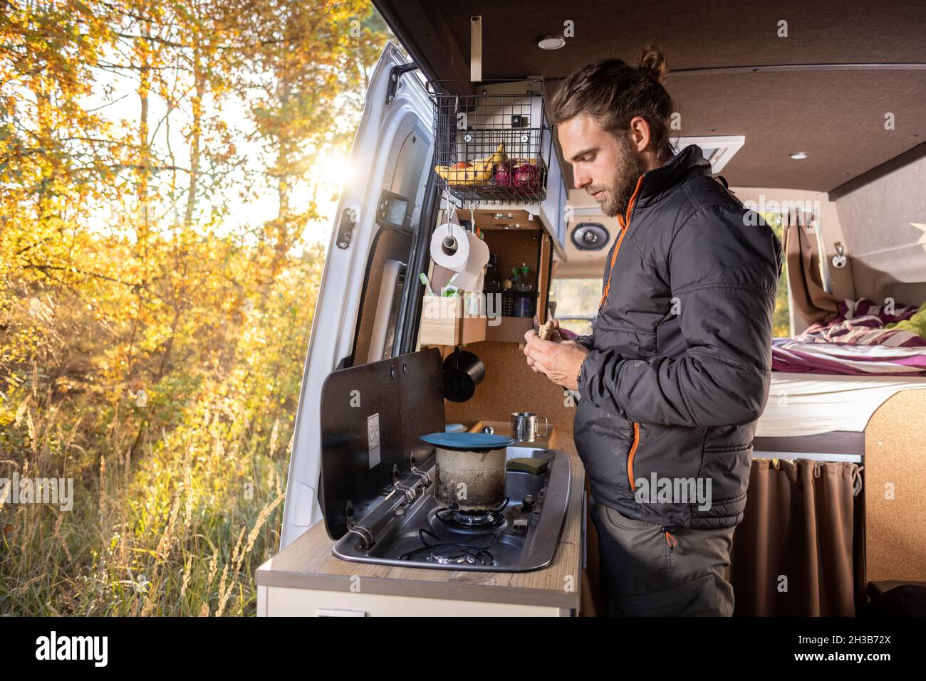 Mann im Küchenbereich seines Wohnwagens im Herbst Stockfoto