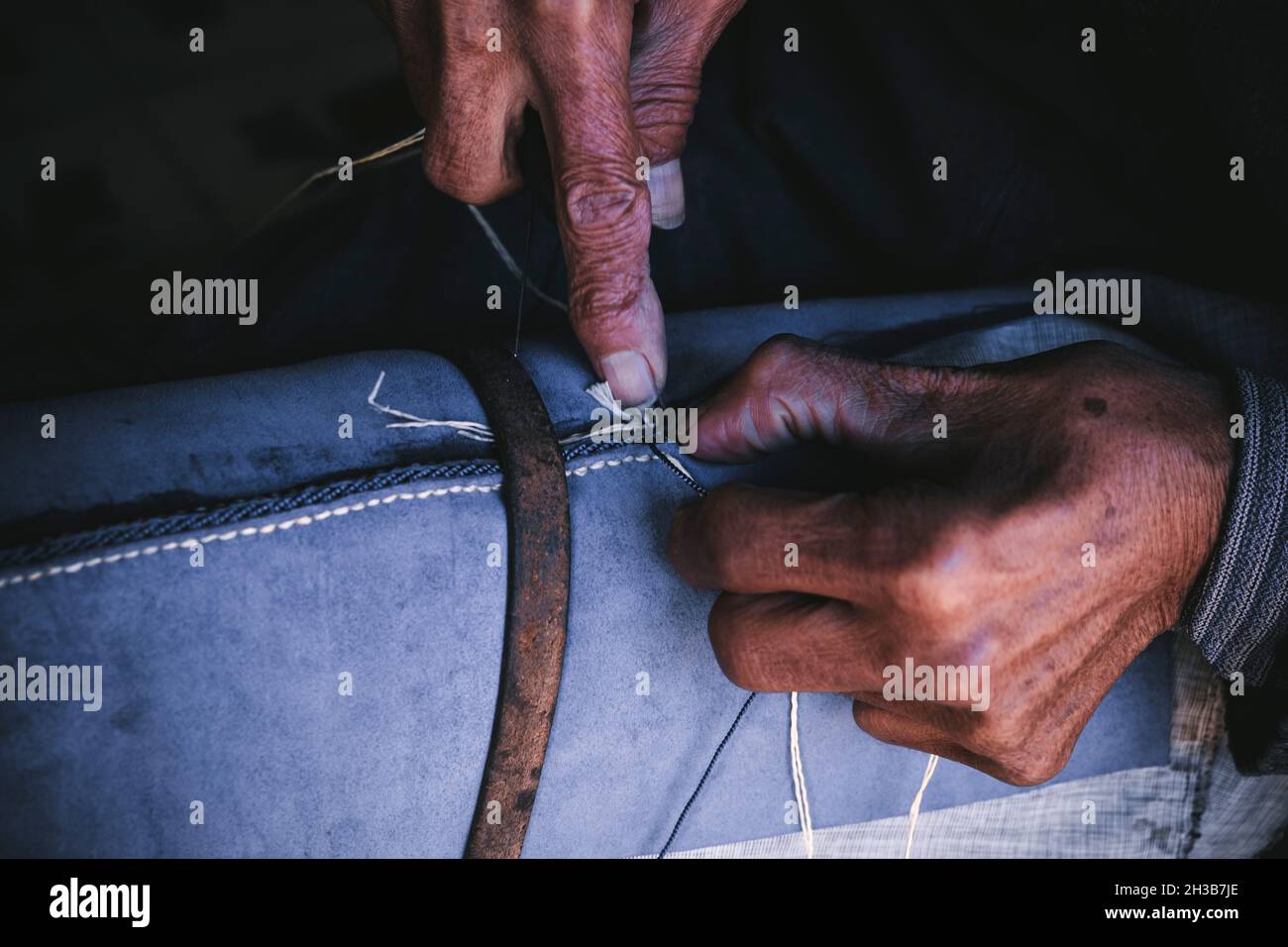 Nahaufnahme der Hände eines alten Mannes beim Nähen Stockfoto
