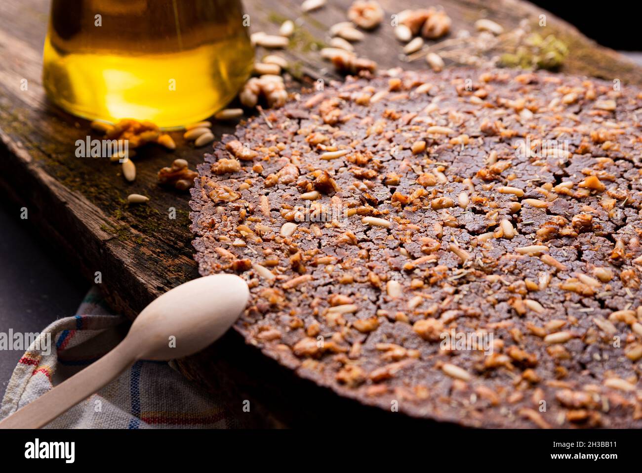 Nahaufnahme des traditionellen Castagnaccio-Kuchens, einer klassischen italienischen glutenfreien Herbstkuchen auf einem Holztisch aus Kastanienmehl, Pinienkernen, Rosmarin und Stockfoto