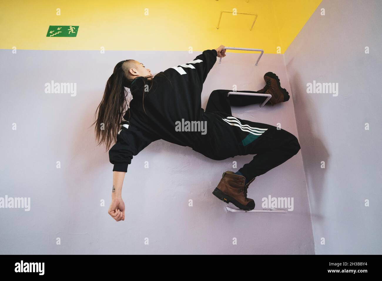 In der Pastellschule hängt eine athletische androgyne starke Frau an den Gittern Stockfoto