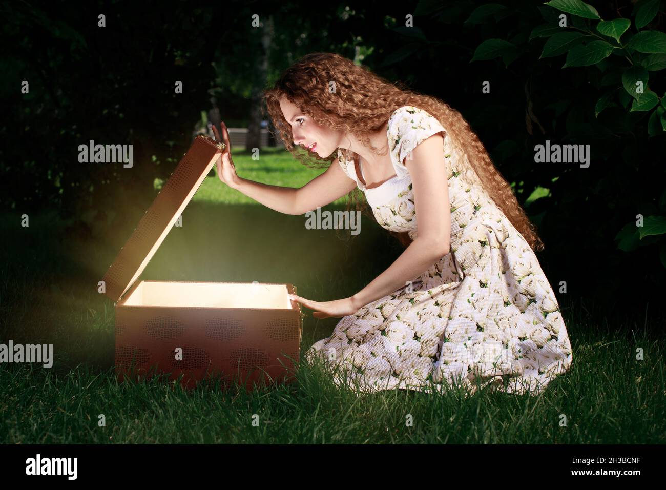 Blonde Mädchen öffnen mystrey Box mit Licht im Inneren Stockfoto