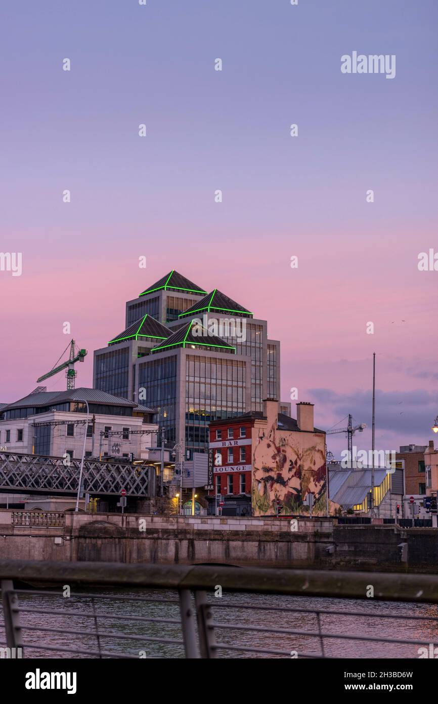 DUBLIN, IRLAND - 04. Apr 2021: Eine vertikale Aufnahme eines alten Büros der Ulster Bank vor einem Fluss bei Sonnenuntergang in Dublin, Irland Stockfoto