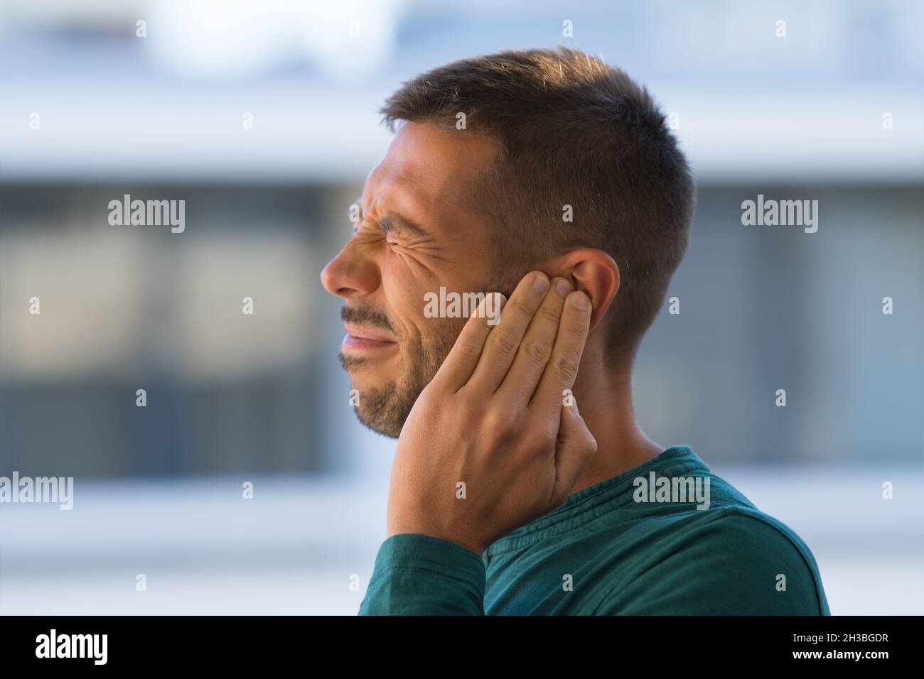 Otitis oder Tinnitus. Mann, der sein Ohr wegen starker Ohrenschmerzen oder Ohrschmerzen berührt. Stockfoto