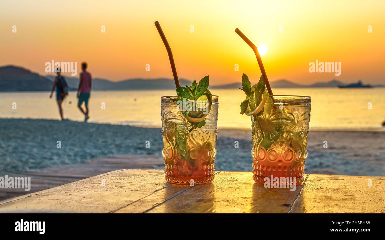 Getränke mit verschwommenem Strand und Sonnenuntergang im Hintergrund Stockfoto