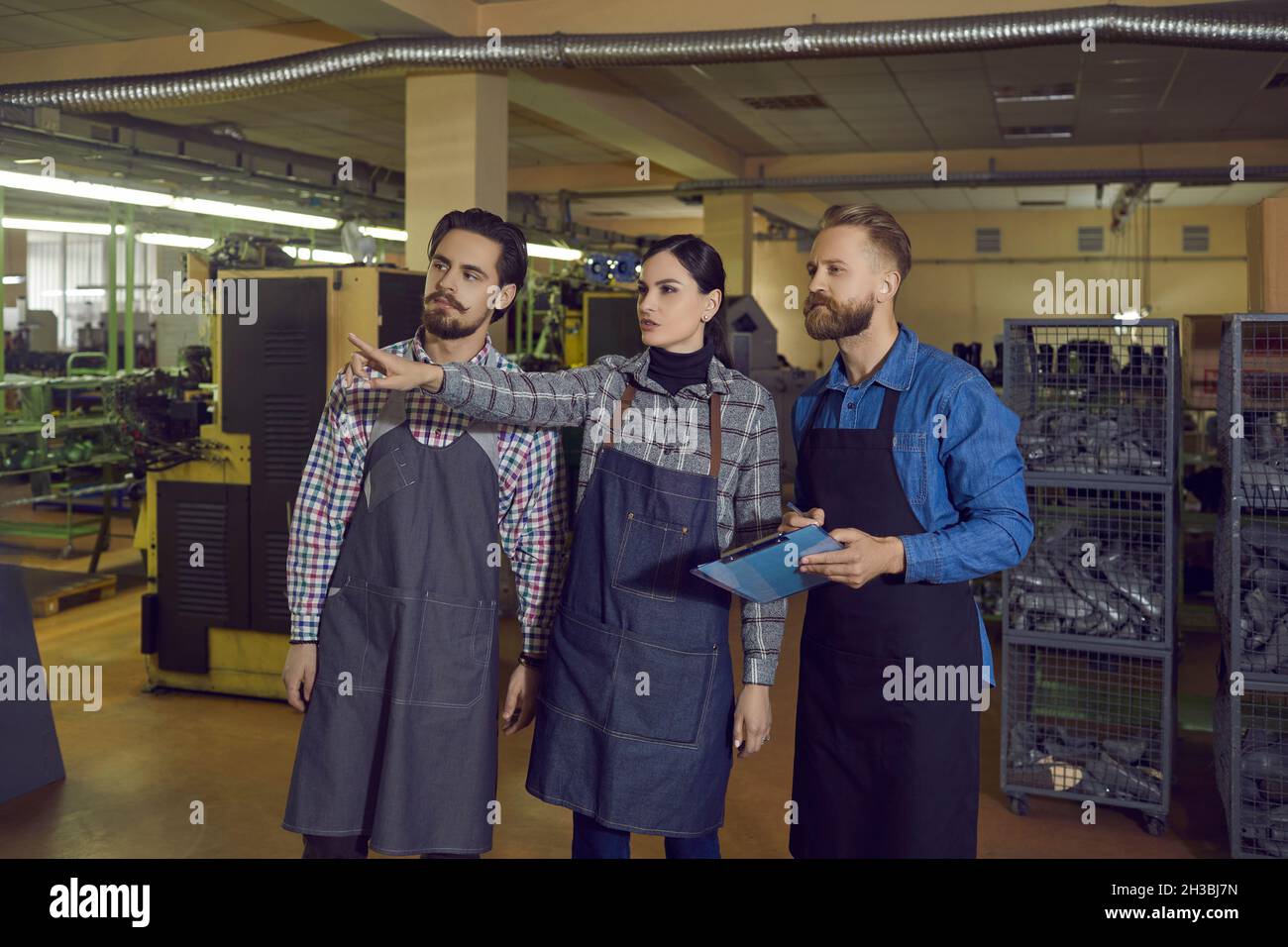 Eine Gruppe von Arbeitern, die dem Besitzer oder Inspektor eine Führung durch die Schuhfabrik geben Stockfoto