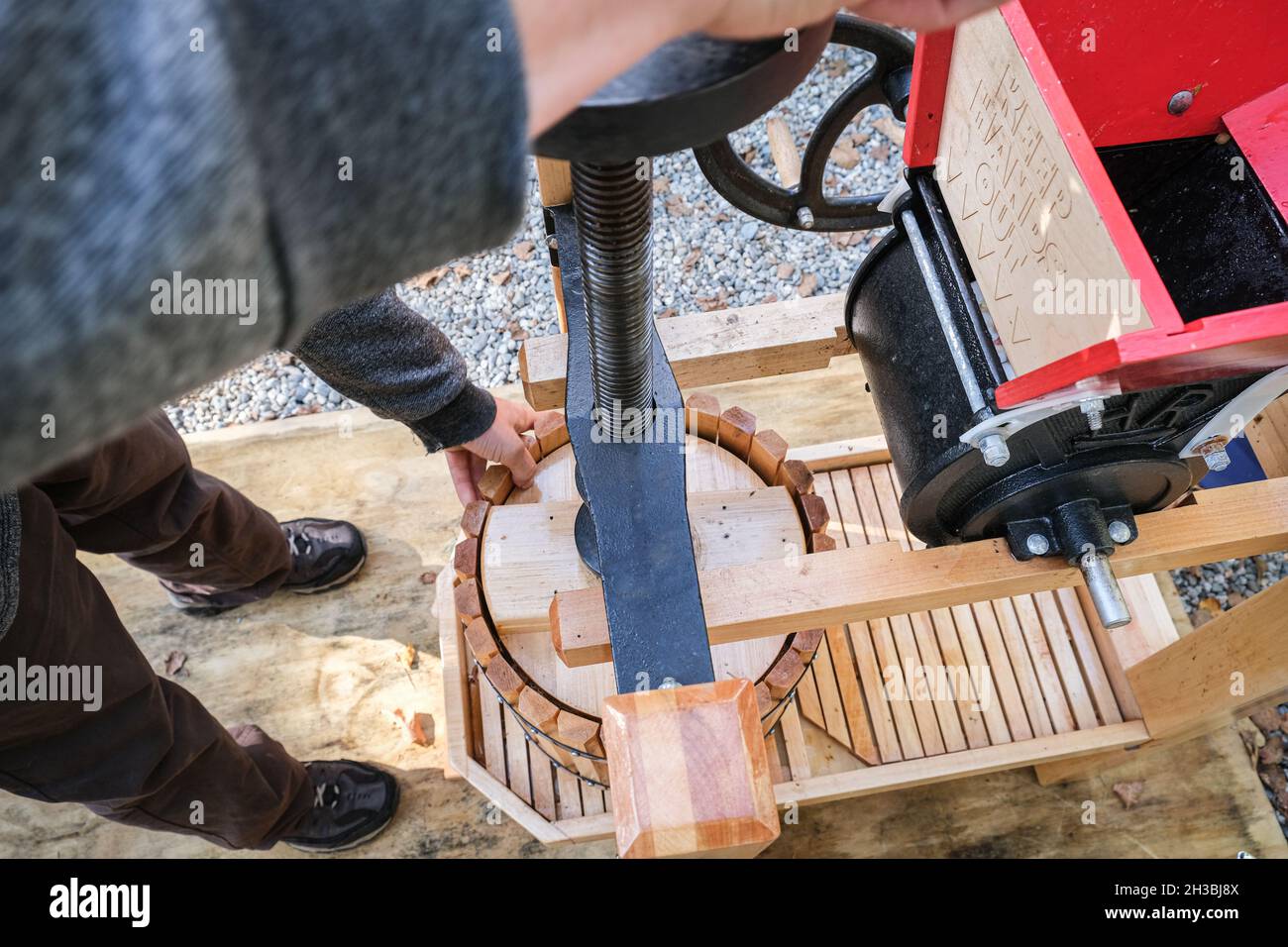 Frische Bio-Äpfel, die durch eine Apfelpresse aus Holz verarbeitet werden. Stockfoto