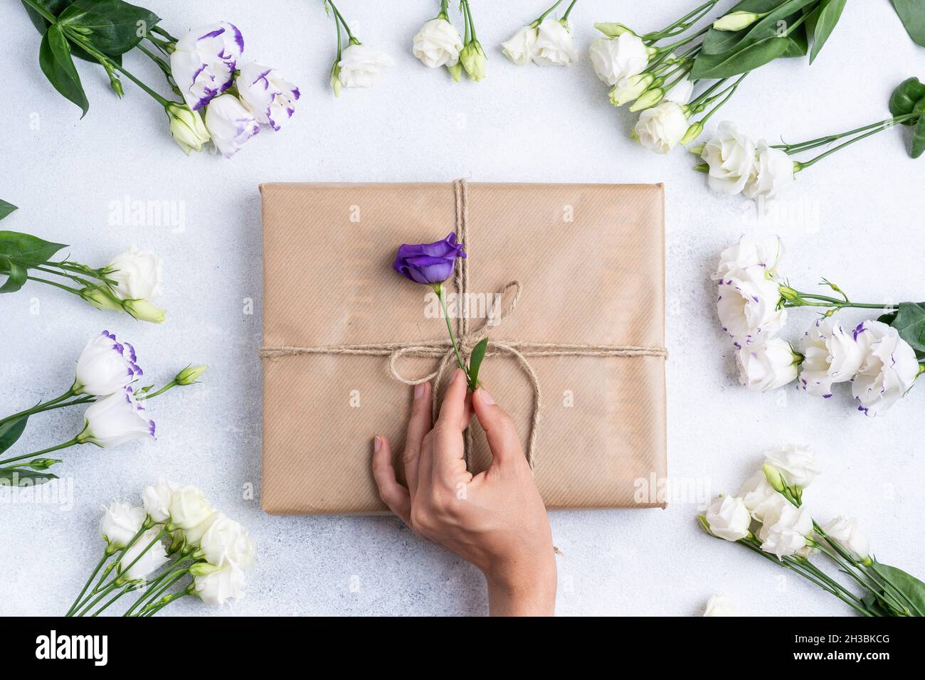 Die Zusammensetzung der Blumen und Taschen. Ein Geschenk und Blumen auf einem rosa Hintergrund. Frauentag, ein Feiertag. Flache Sonnenliege, Draufsicht, Kopierbereich. Stockfoto