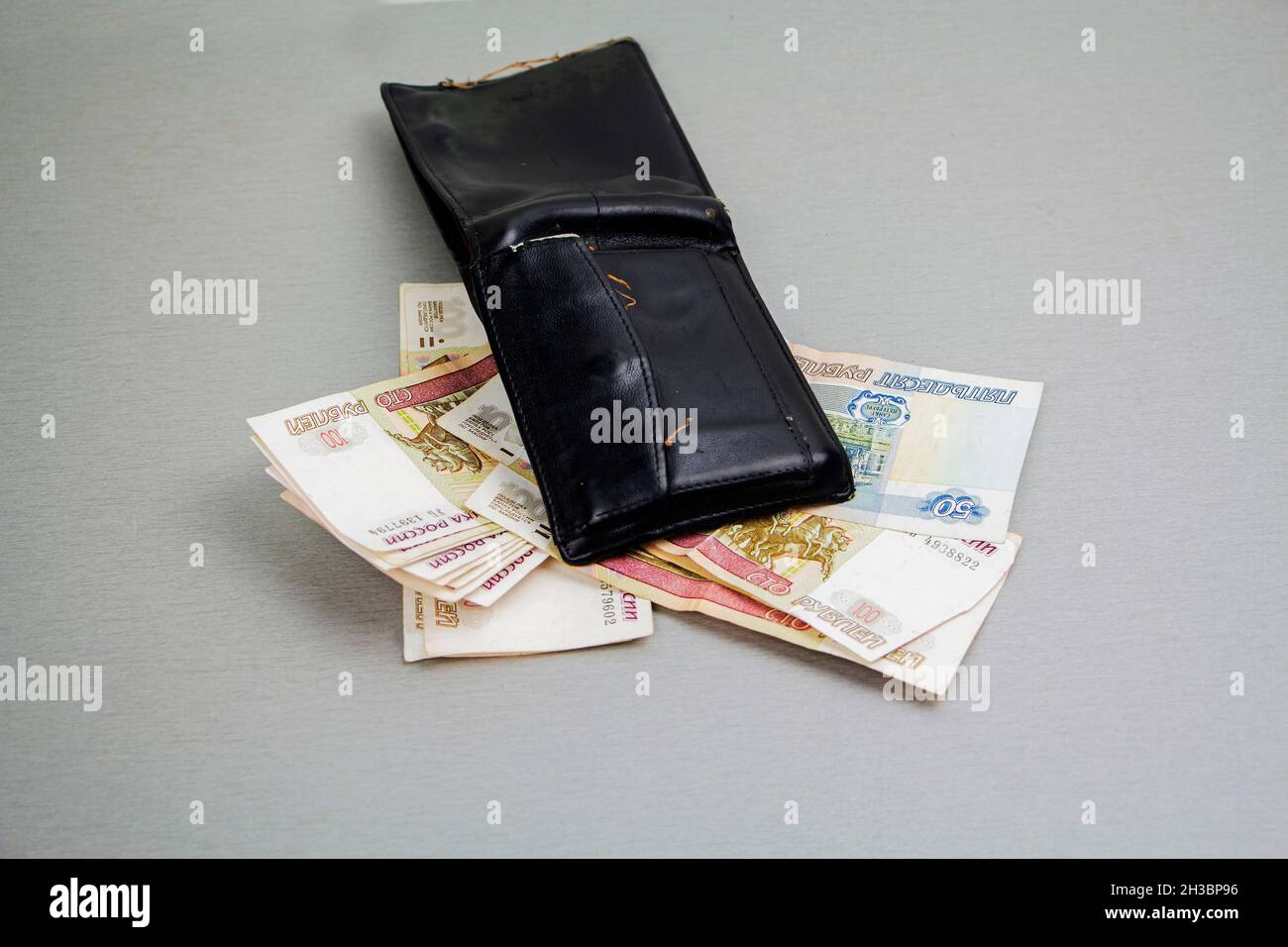 Retro-schwarze Brieftasche und Banknoten von 1000 und 100 Rubel ragen heraus. Wirtschaft und Finanzen, das Konzept des Reichtums. Krise. Stockfoto