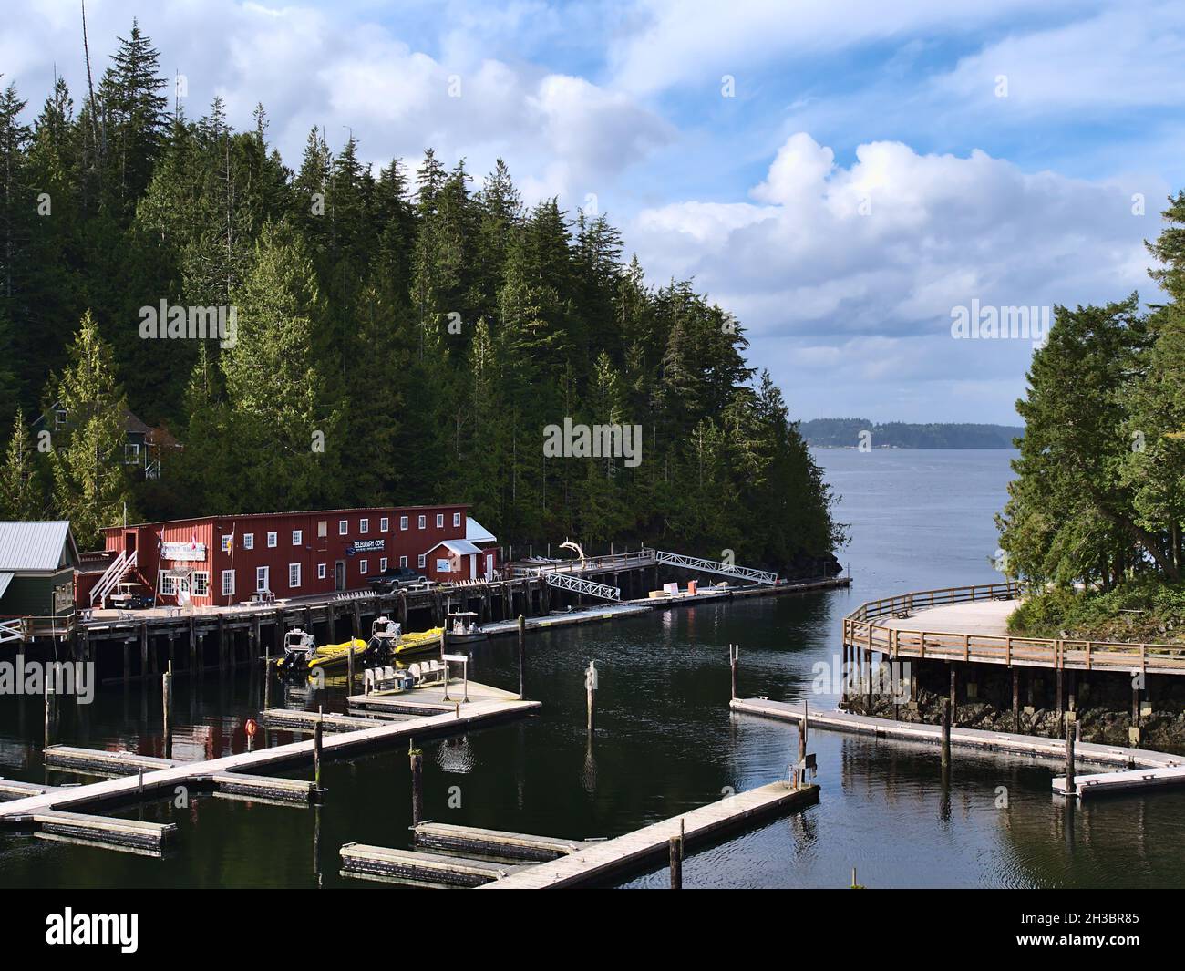 Blick auf das Hafenbecken von Telegraph Cove, Vancouver Island im Herbst (Nebensaison) mit Gebäuden auf Stelzen, Pier und Walbeobachtungsbooten. Stockfoto