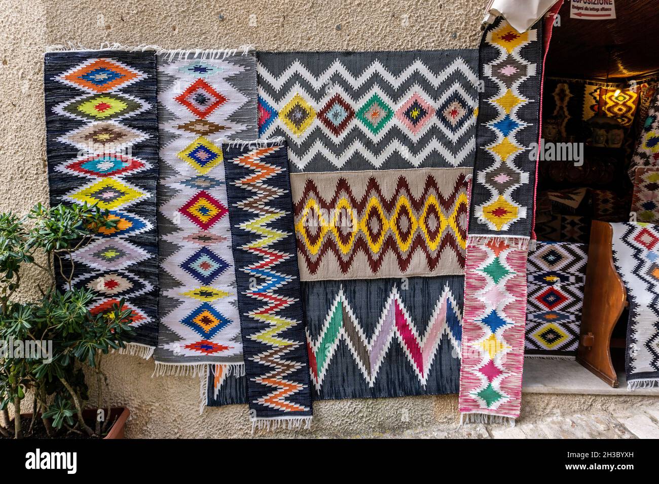 Ein Geschäft, das traditionelle Teppiche verkauft einer der vielen Kunsthandwerksläden, die in den engen Kopfsteinpflasterstraßen von Erice in Sizilien, Italien, leben. Stockfoto