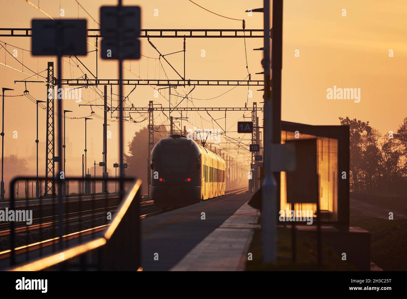 Eisenbahn bei Sonnenaufgang. Passagierzug vom Bahnhof. Stockfoto
