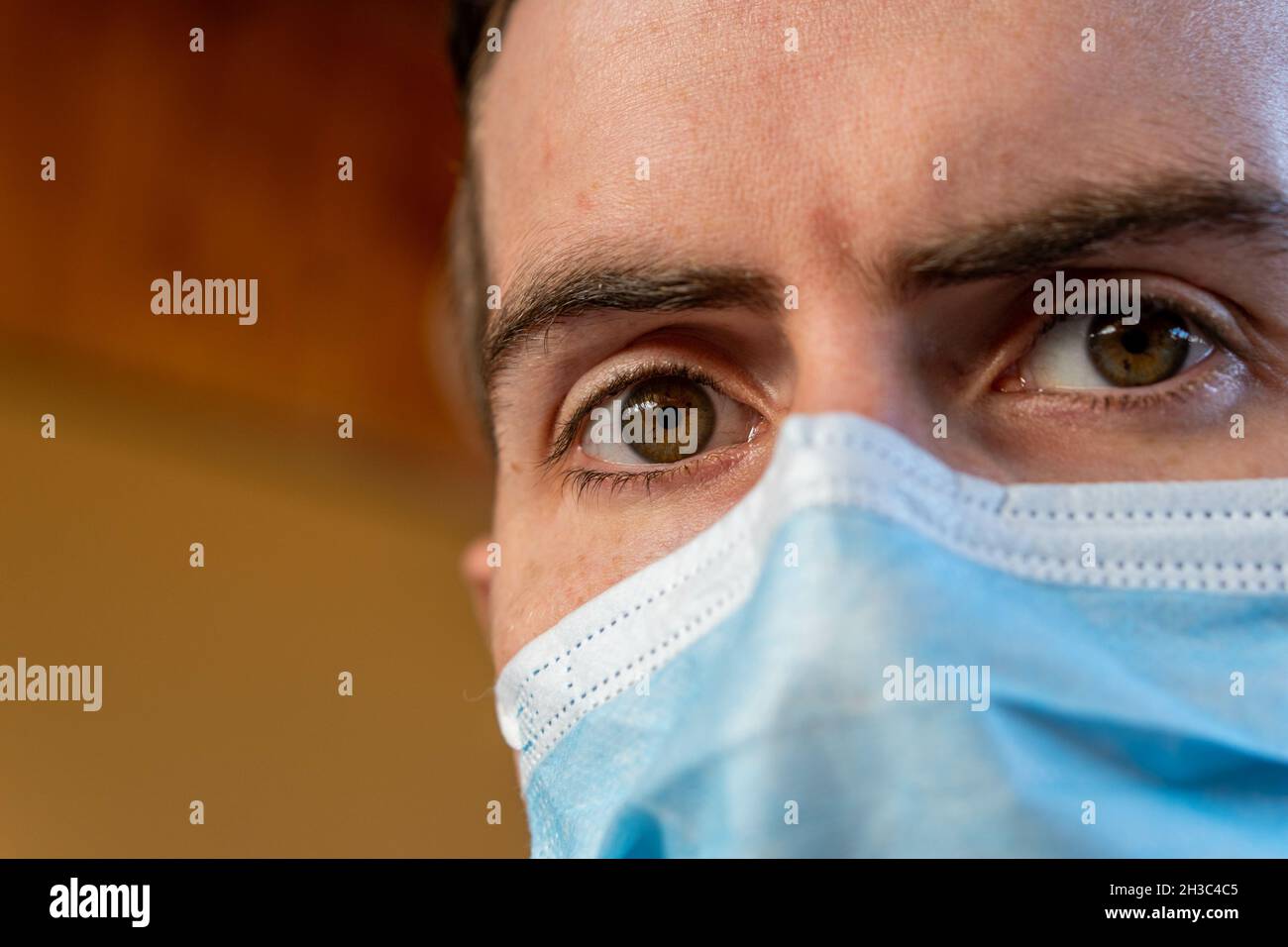 Junger hispanischer Typ mit zentraler Heterochromie, der eine Damenmaske trägt und die Kamera anschaut Stockfoto