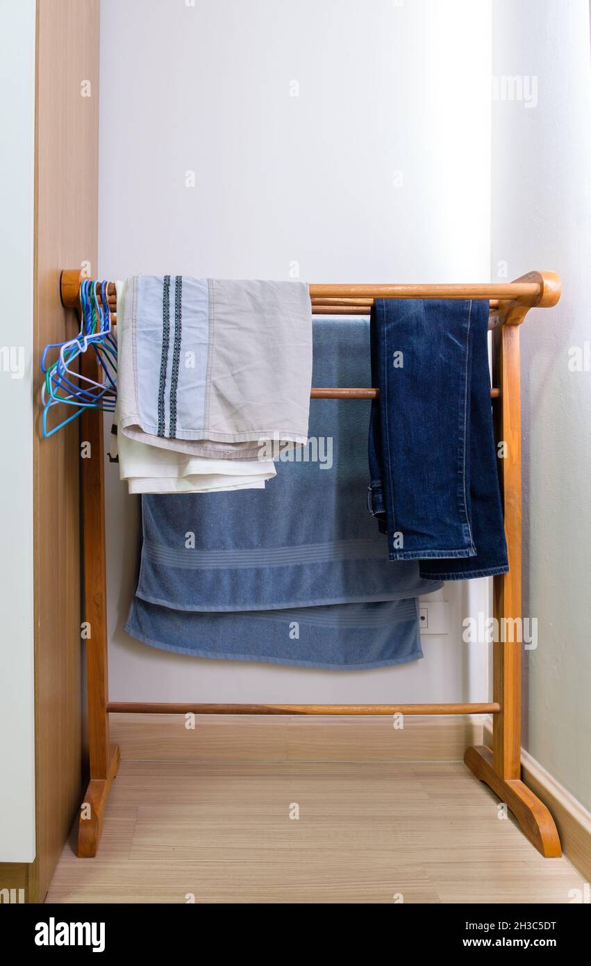 Die hölzerne Wäscheleine mit dem Handtuch und Jeans und Männershorts in der Nähe des großen Kleiderschranks im Schlafzimmer des Stadthauses, Vorderansicht mit der Kopie sp Stockfoto