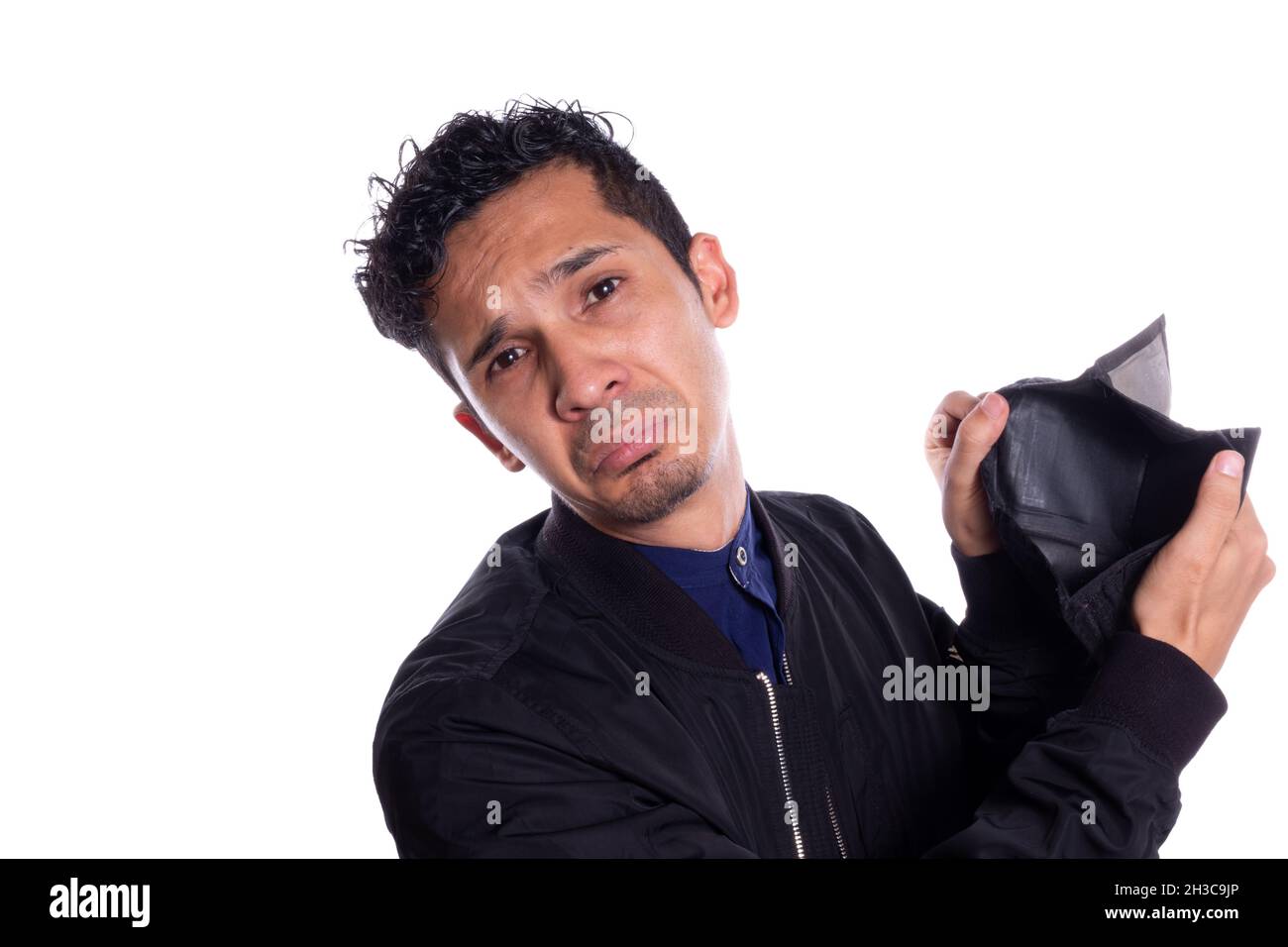 Trauriger Mann, der der Kamera seine leere Brieftasche zeigt, isoliert auf weißem Hintergrund. Ausdruck eines jungen Erwachsenen frustriert, weil er kein Geld oder Ersparnisse hat. Stockfoto
