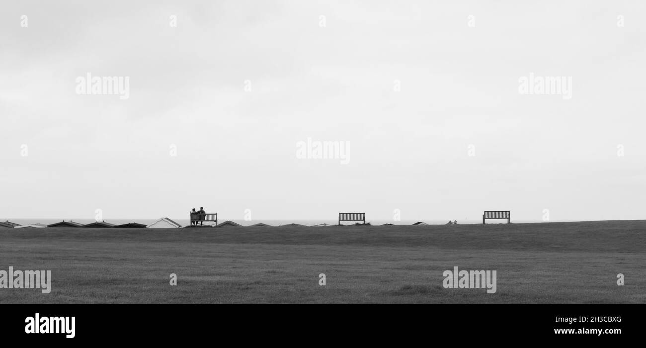 Monochrom-Bild von drei Sitzen in der Ferne mit weißem Himmel darüber Stockfoto