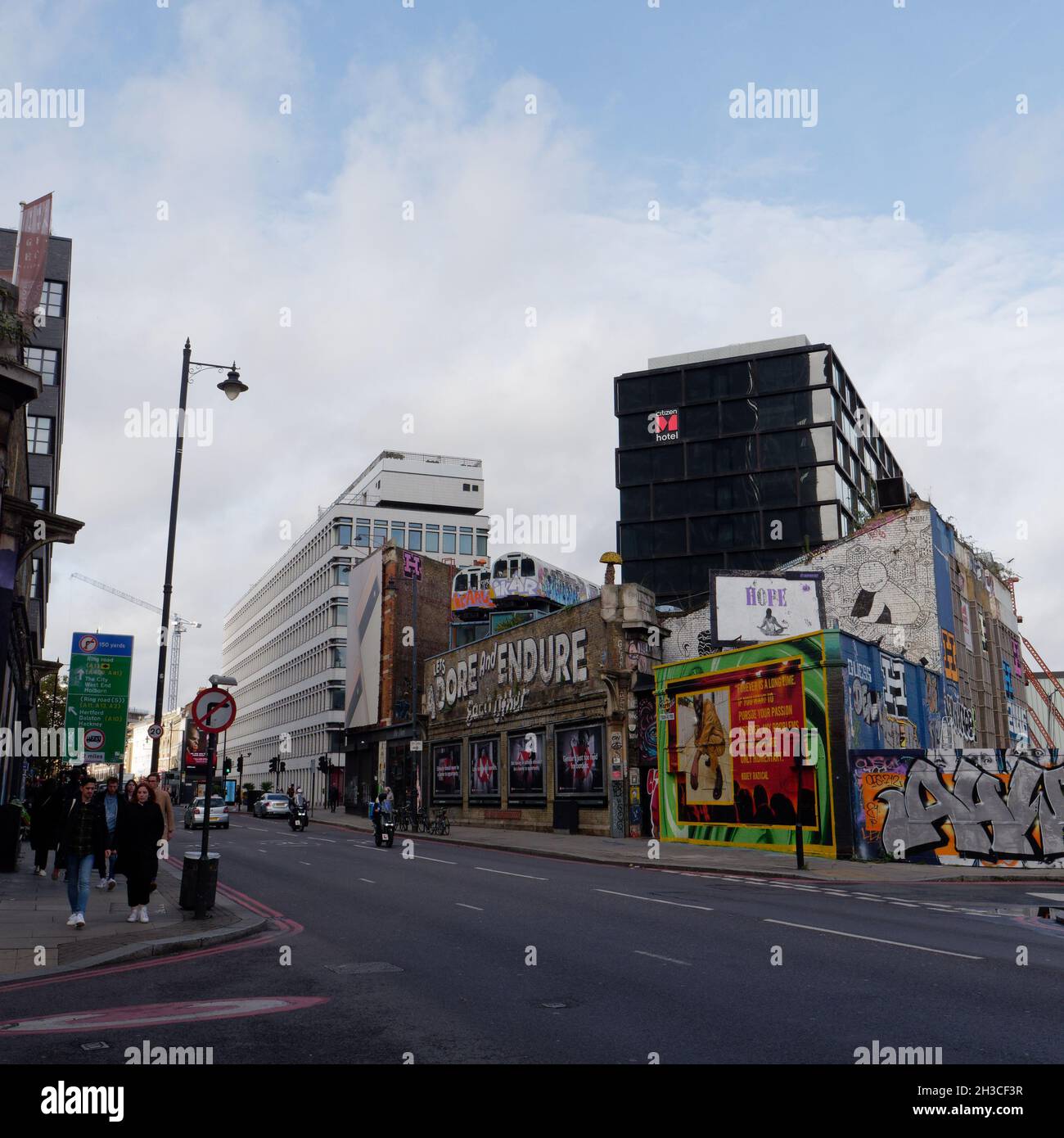 Great Eastern Street in Shoreditch mit den berühmten Lets anbeten und ertragen einander Schild und U-Bahn-Züge über einem Gebäude. London Stockfoto