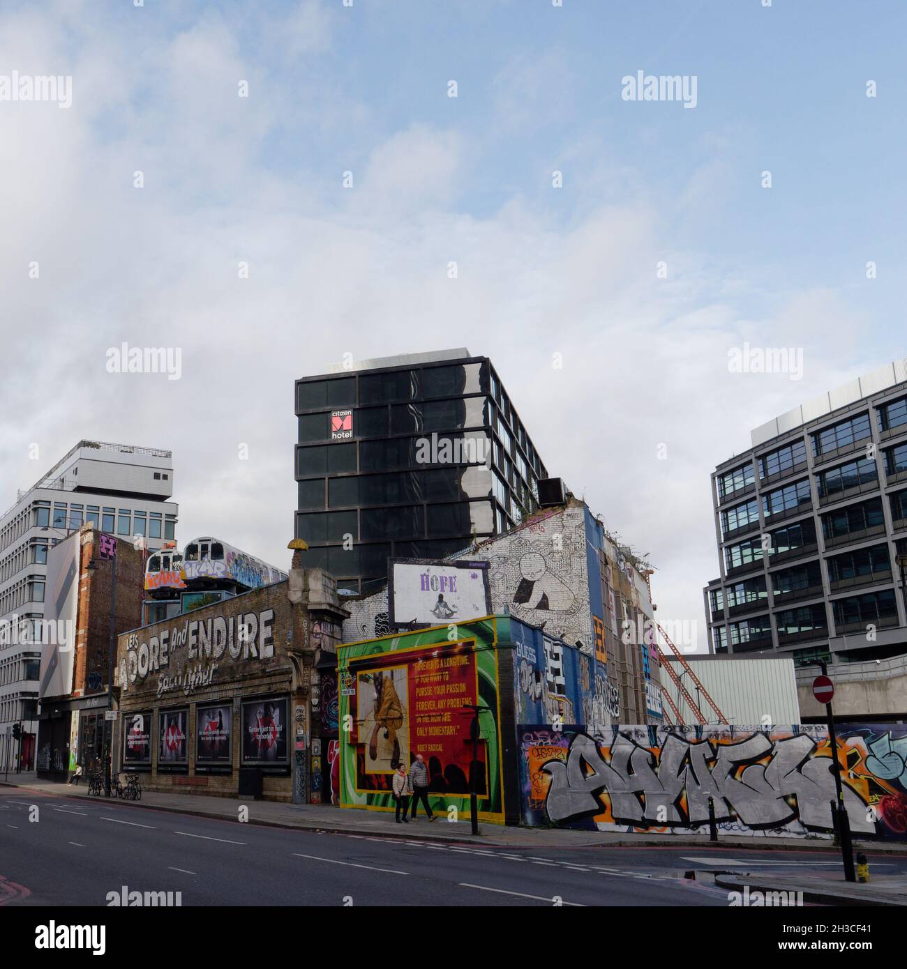 Great Eastern Street in Shoreditch mit den berühmten Lets anbeten und ertragen einander Schild und U-Bahn-Züge über einem Gebäude. London Stockfoto