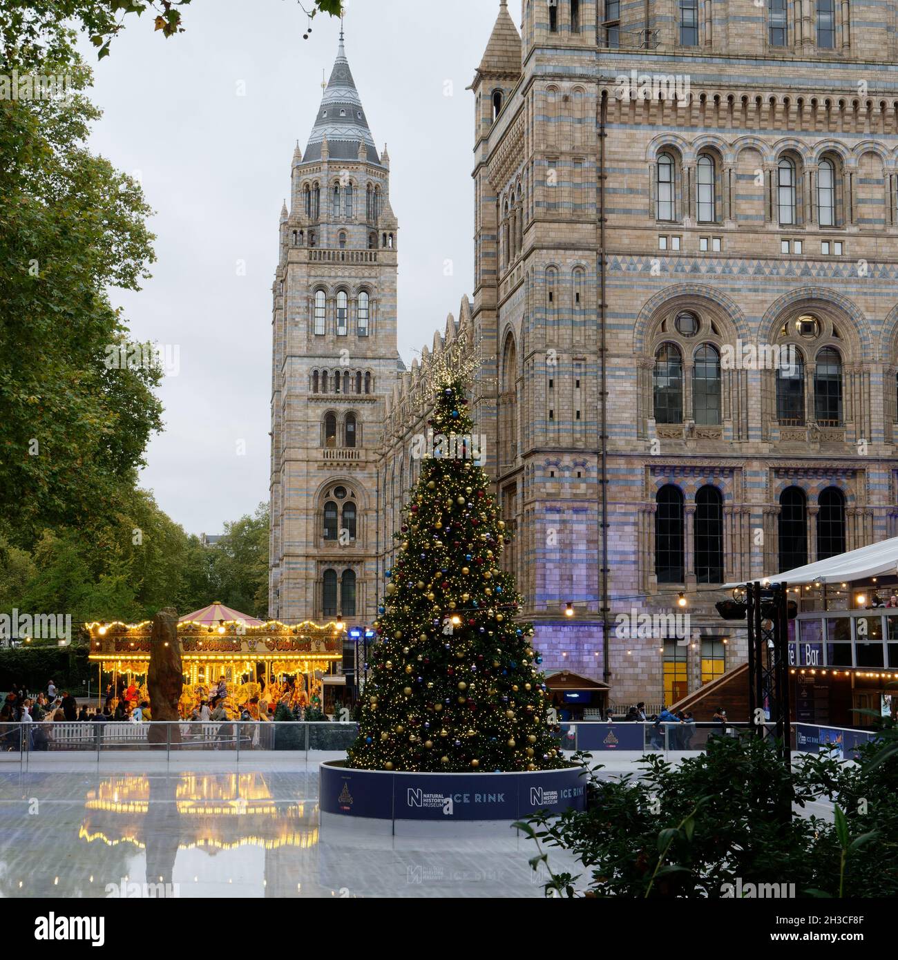 London, Greater London, England, 26 2021. Oktober: Festliche Eisbahn im National History Museum mit Weihnachtsbaum und Merry Go Round. Stockfoto