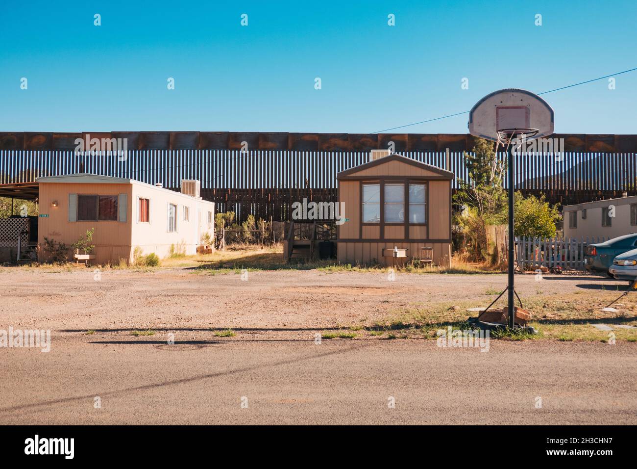 Ein Basketballkorb auf der Straße in der US-Grenzstadt Naco, Arizona. Dahinter ragt die hohe, verrostete Stahlgrenzmauer zwischen den USA und Mexiko Stockfoto