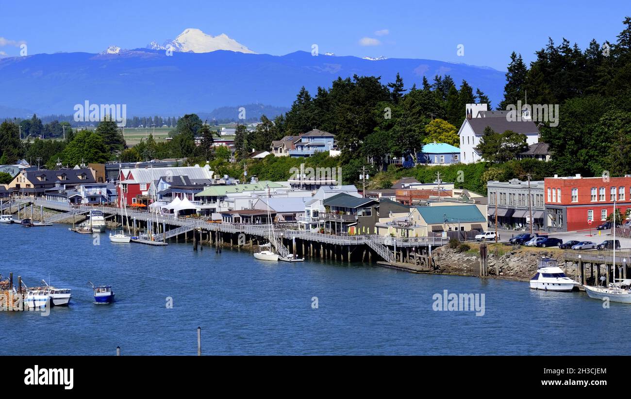 REGENBOGENBRÜCKE BLICK AUF DAS MALERISCHE DORF LA CONNER, WASHINGTON UND DEN SWINOMISH CHANN ... MIT MT BAKER UND DEN WASHINGTON KASKADEN IN DER FERNE. Stockfoto