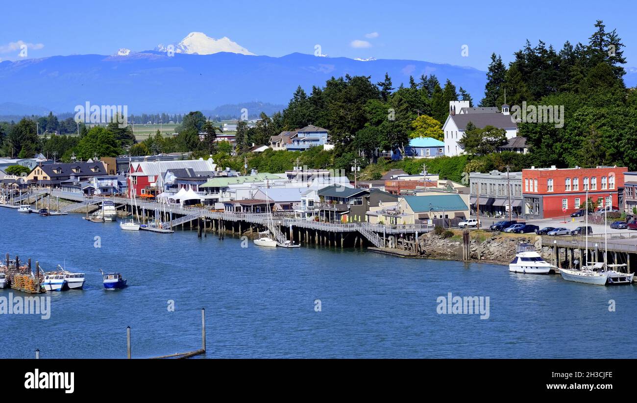 REGENBOGENBRÜCKE BLICK AUF DAS MALERISCHE DORF LA CONNER, WASHINGTON UND DEN SWINOMISH CHANN ... MIT MT BAKER UND DEN WASHINGTON KASKADEN IN DER FERNE. Stockfoto