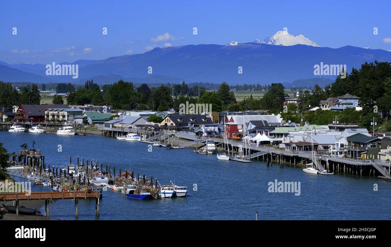 REGENBOGENBRÜCKE BLICK AUF DAS MALERISCHE DORF LA CONNER, WASHINGTON UND DEN SWINOMISH CHANN ... MIT MT BAKER UND DEN WASHINGTON KASKADEN IN DER FERNE. Stockfoto