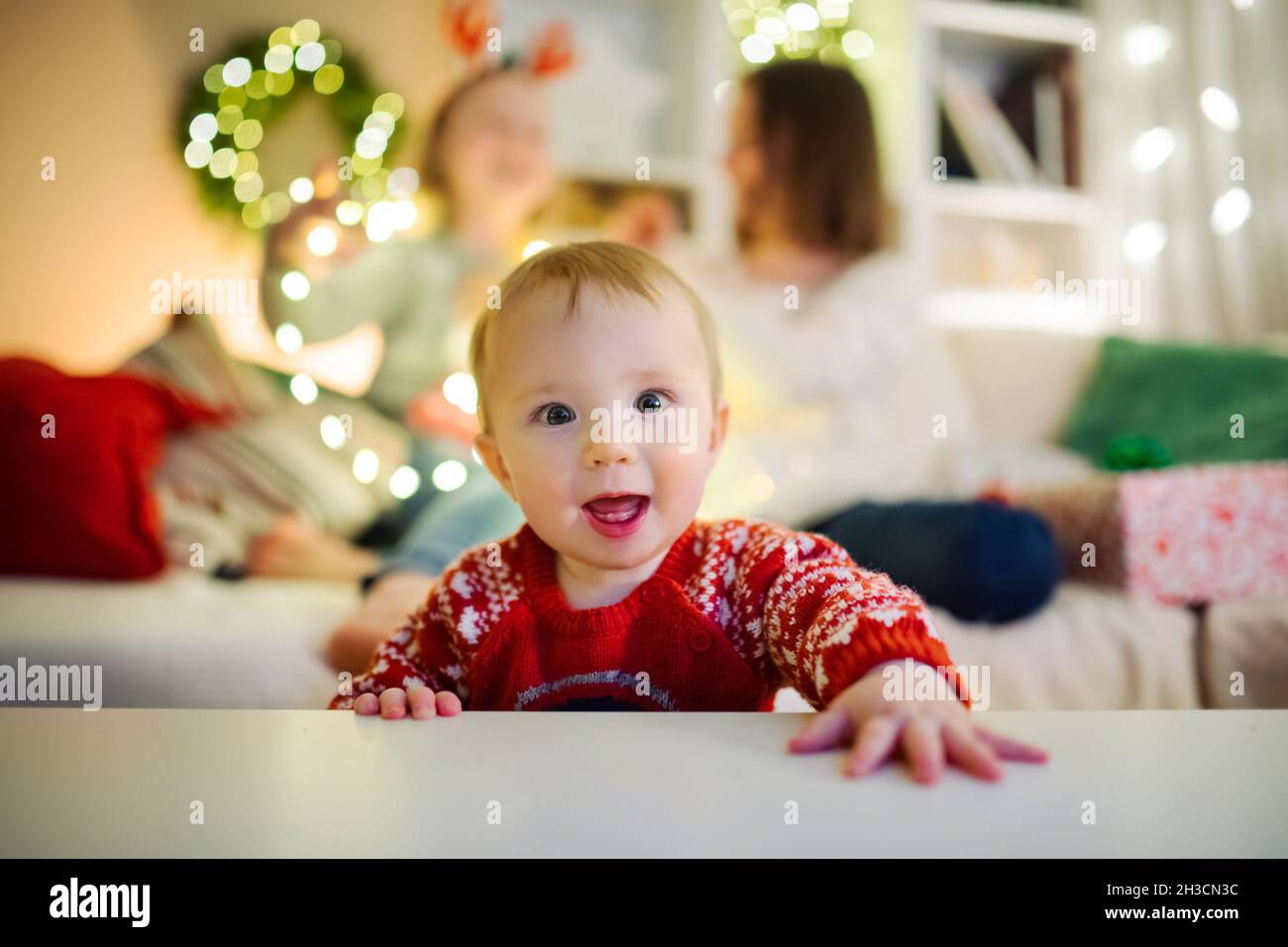 Glücklicher kleiner Junge, der Spaß mit seiner Familie in einem gemütlichen Wohnzimmer am Heiligabend hat. Weihnachten zu Hause feiern. Winterabend mit Familie und Kindern Stockfoto