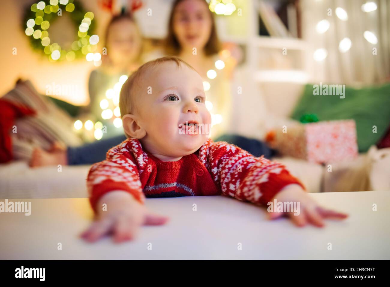 Glücklicher kleiner Junge, der Spaß mit seiner Familie in einem gemütlichen Wohnzimmer am Heiligabend hat. Weihnachten zu Hause feiern. Winterabend mit Familie und Kindern Stockfoto