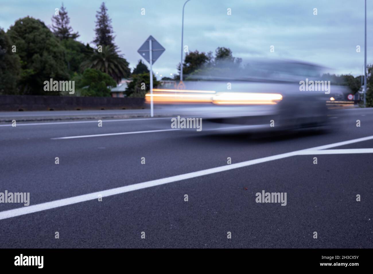 Autobahn mit weißen Straßenmarkierungen und verschwommenem Bild von vorbeifahrenden Fahrzeugen auf dem Tauranga Takitimu Drive Expressway. Stockfoto