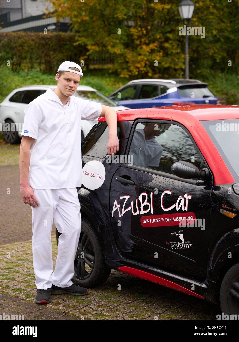 Daaden, Deutschland. Oktober 2021. Auszubildender Veit Benfer steht vor dem 'Azubi Car', einem Kleinwagen, den Metzgermeister Dirk Schmidt seinen Auszubildenden zur Verfügung stellt. Das Unternehmen in Daaden (Kreis Altenkirchen) beschäftigt 30 Mitarbeiter, davon 5 Auszubildende. (An dpa: 'Speeddating and Azubi Car - Creative advertising for New Blood'). Quelle: Thomas Frey/dpa/Alamy Live News Stockfoto