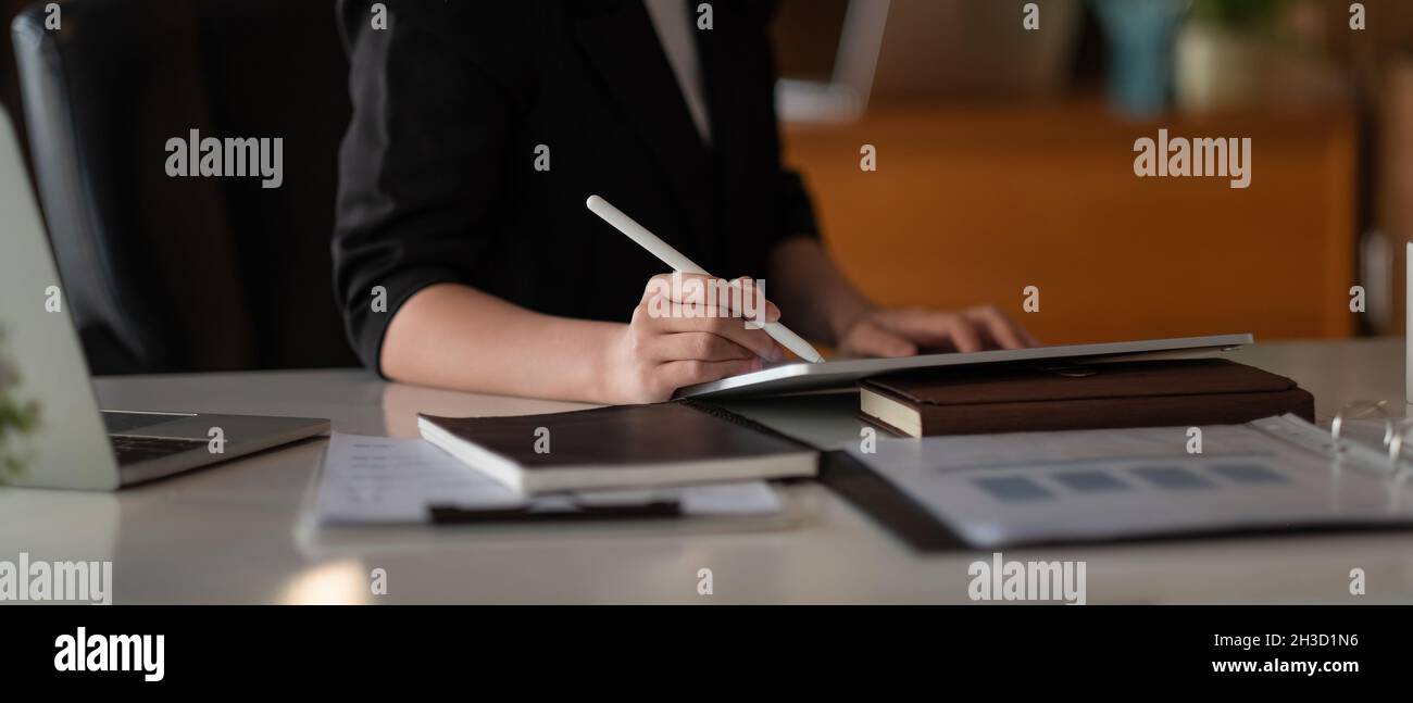 Nahaufnahme der Frau mit Stylus Pen Schreiben auf dem digitalen Tablet, berühren auf dem digitalen Tablet-Bildschirm arbeiten auf Laptop-Computer im Büro Stockfoto