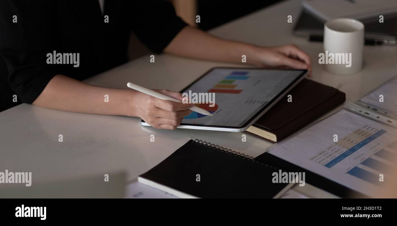 Nahaufnahme der Frau mit Stylus Pen Schreiben auf dem digitalen Tablet, berühren auf dem digitalen Tablet-Bildschirm arbeiten auf Laptop-Computer im Büro Stockfoto