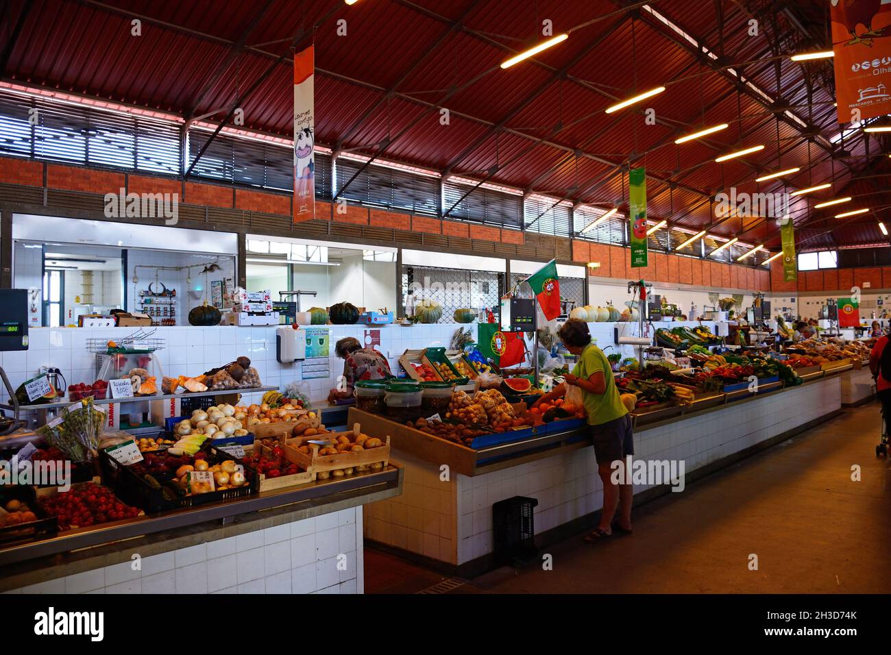 Käufer, die auf frische Produkte für den Verkauf in der Markthalle, Olhau, Algarve, Portugal, Europa. Stockfoto