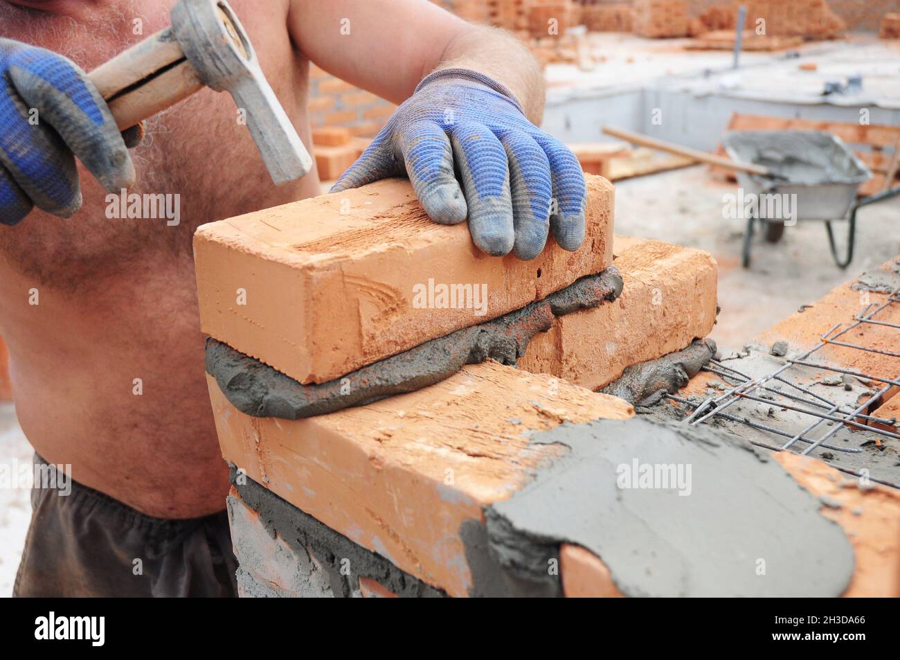 Wie man Ziegel legt: Maurer Ziegelsteine mit Hammer legen. Mauerwerk. Stockfoto