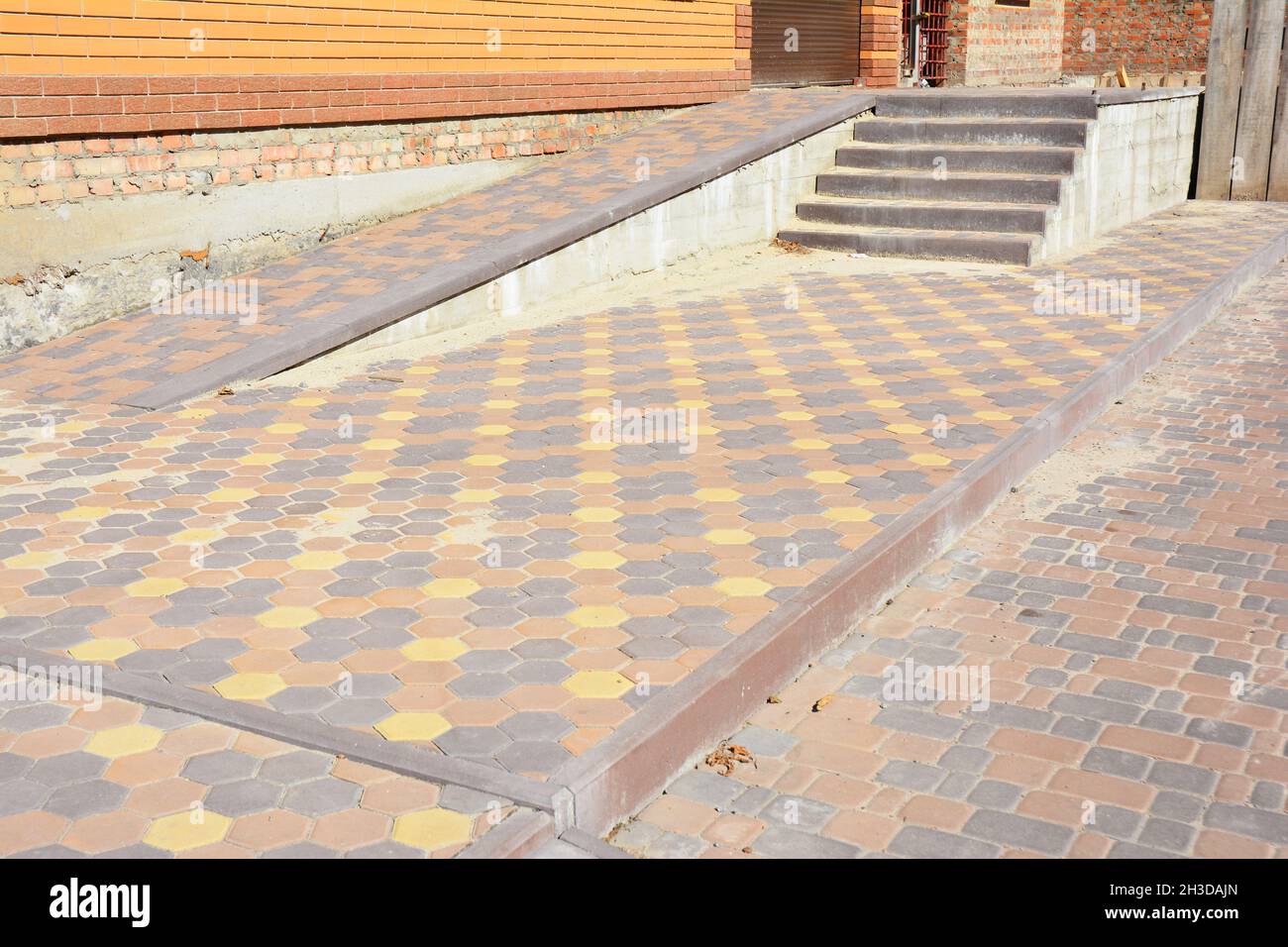 Nahaufnahme auf einer Backsteinrampe zur Unterstützung von Rollstuhlbehinderten Menschen im Neubau eines Hauses. Stockfoto