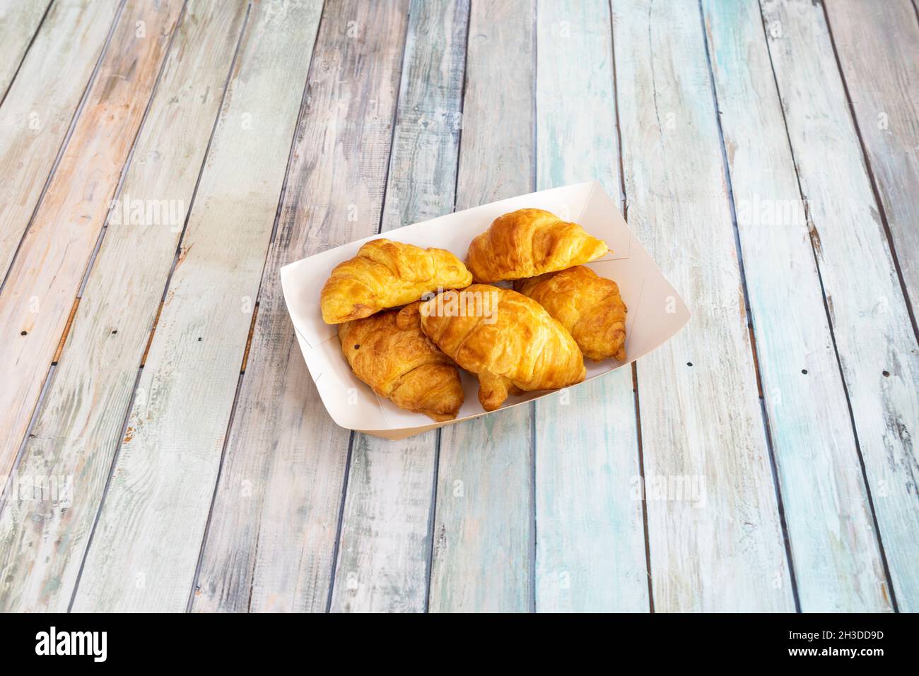 Kleines Tablett zum Mitnehmen mit Buttercroissants auf einem Holztisch Stockfoto